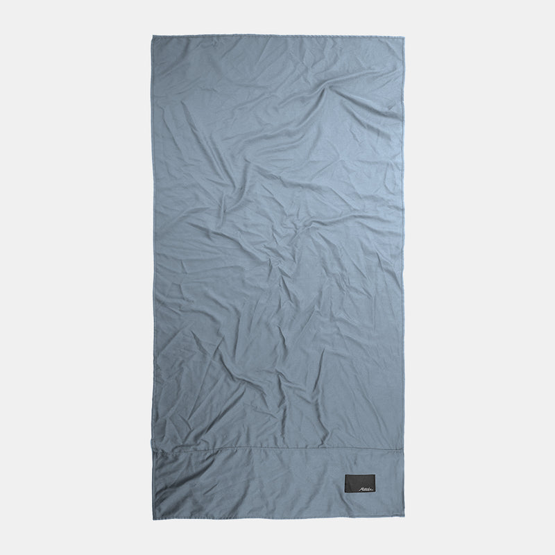 Top-down view of full slate blue towel on light gray background