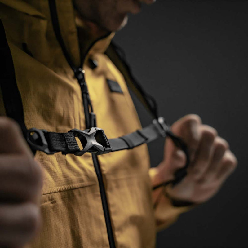 Close up view of backpack sternum strap buckled on man in yellow jacket