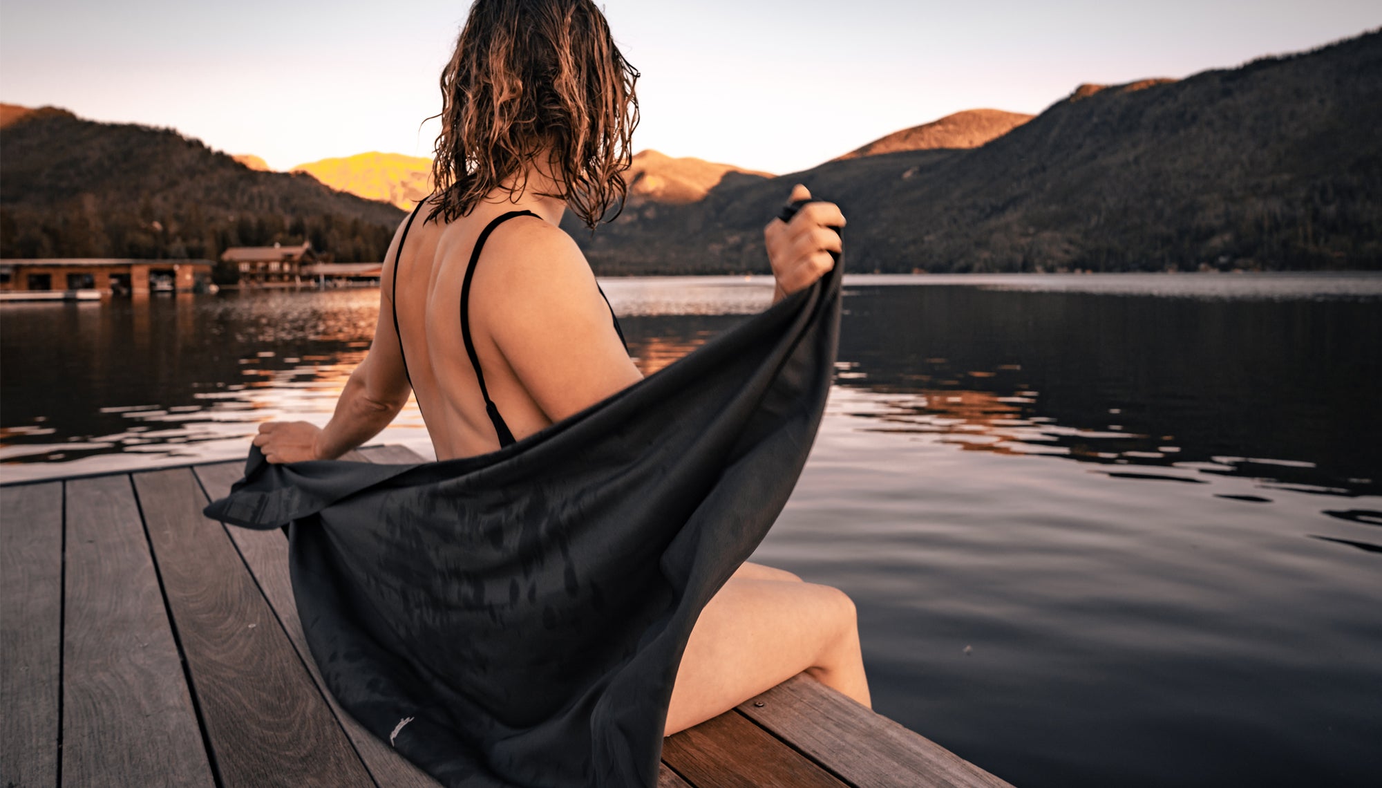 Woman at sunset lake, wrapping herself in a NanoDry towel