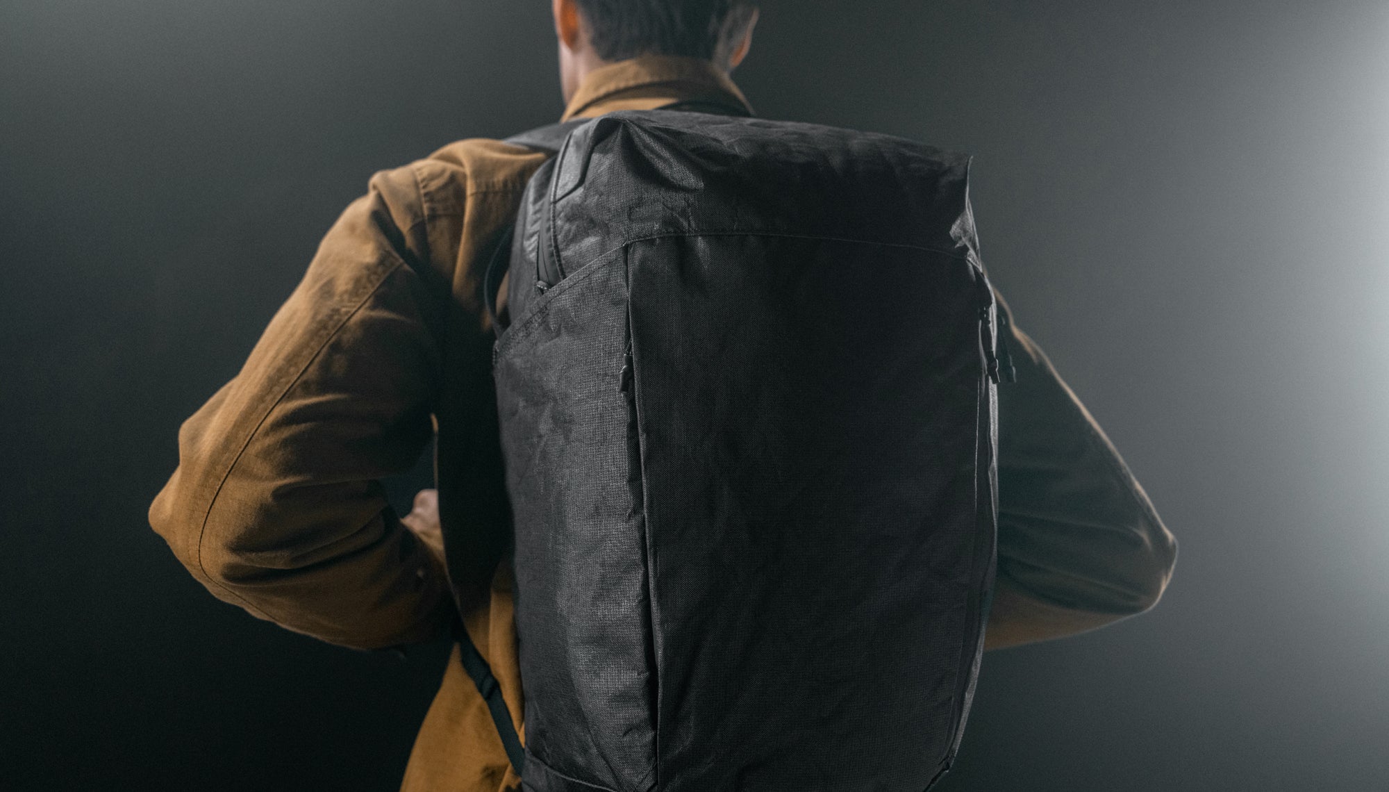 man on dark studio background wearing black backpack