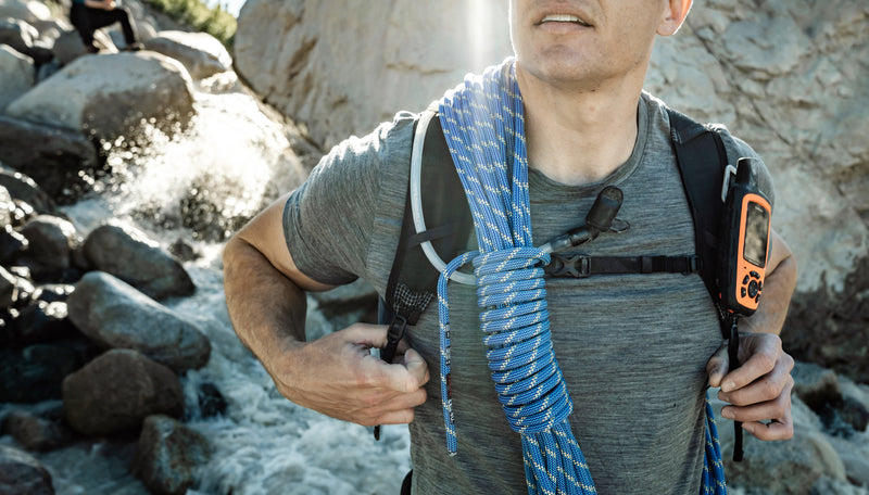 Man in alpine setting, wearing Freerain28 backpack, climbing rope, and GPS device