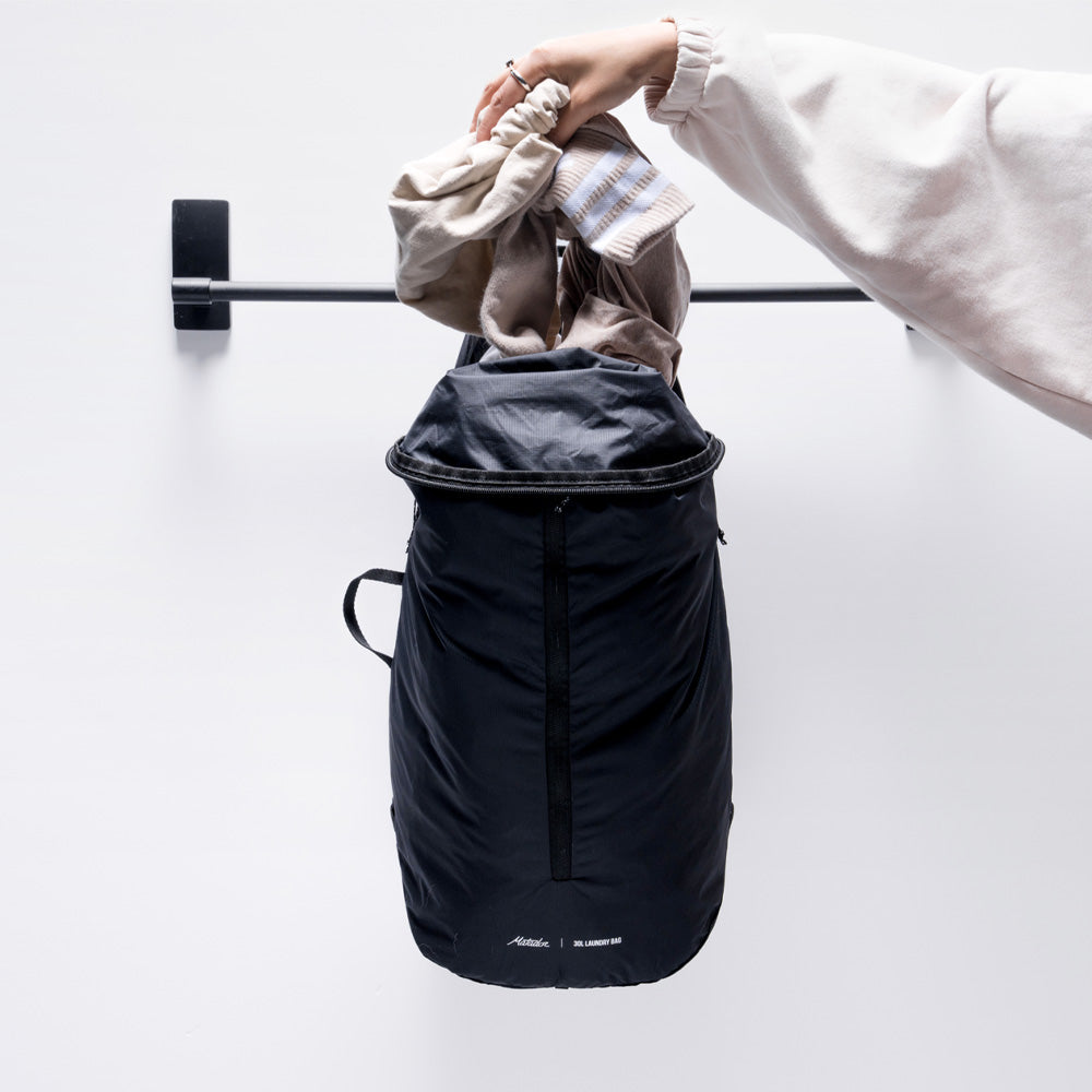 close up view of woman placing laundry into bag hanging from towel rod
