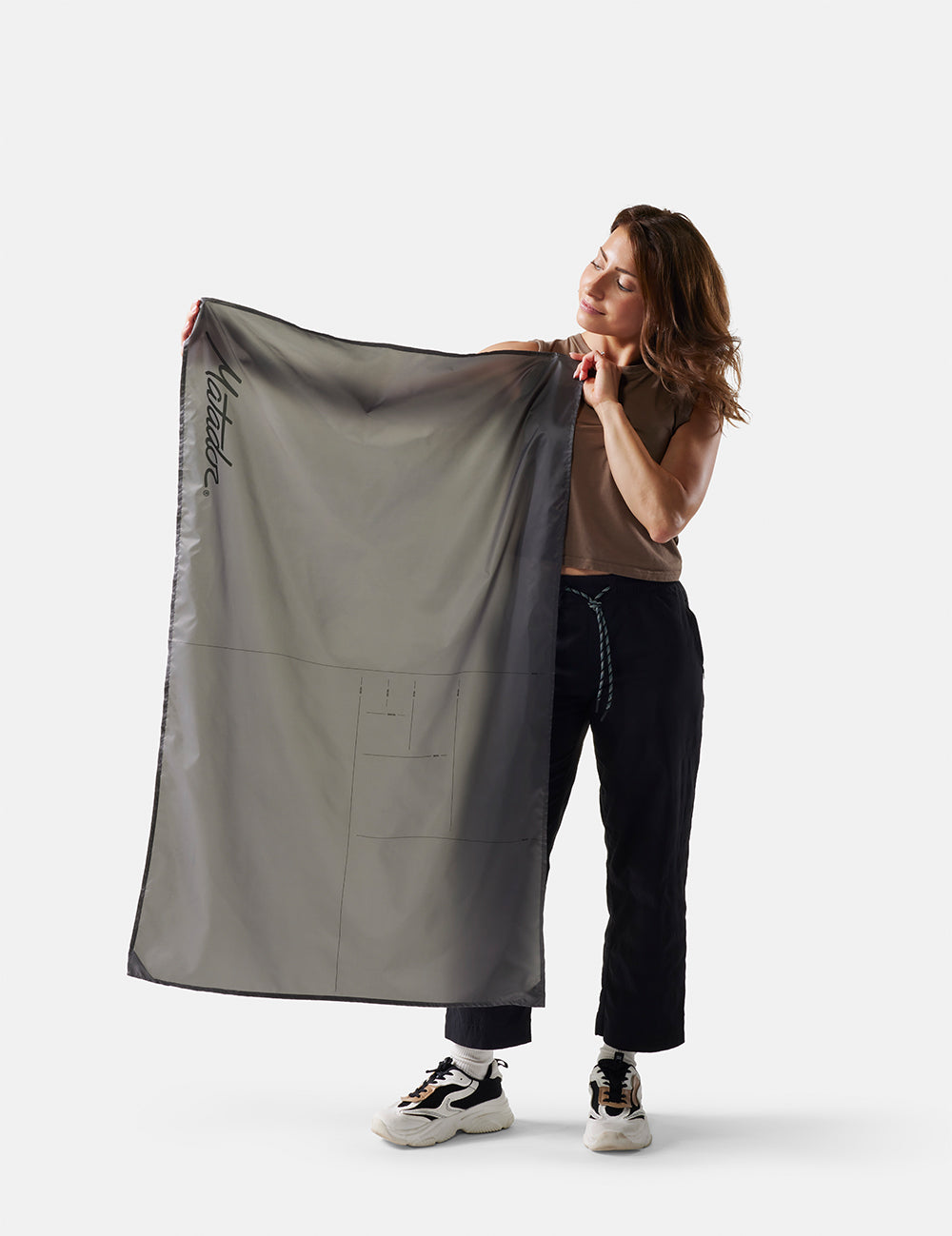 Person holding a large gray fabric item on a white background