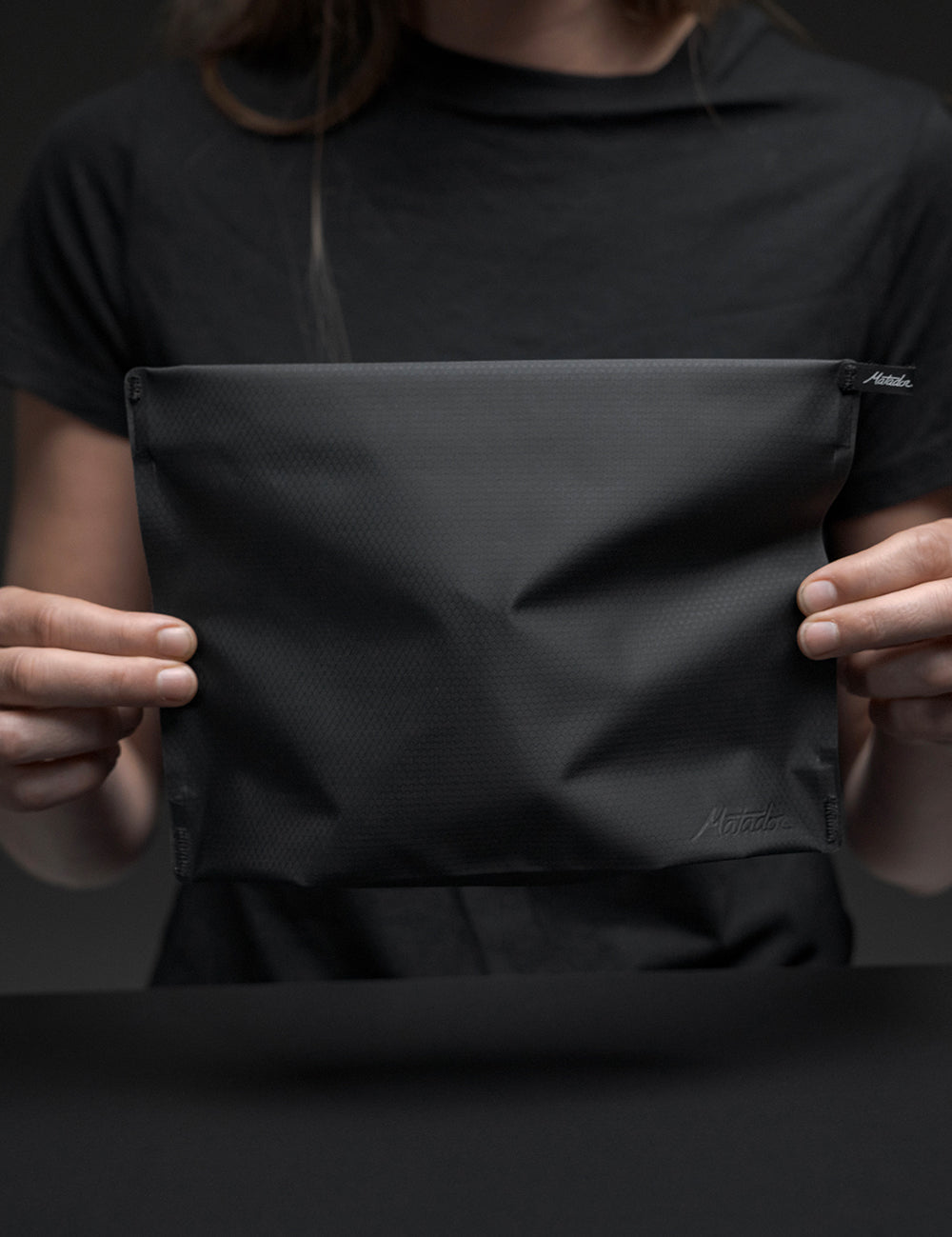 woman in black holding black toiletry case
