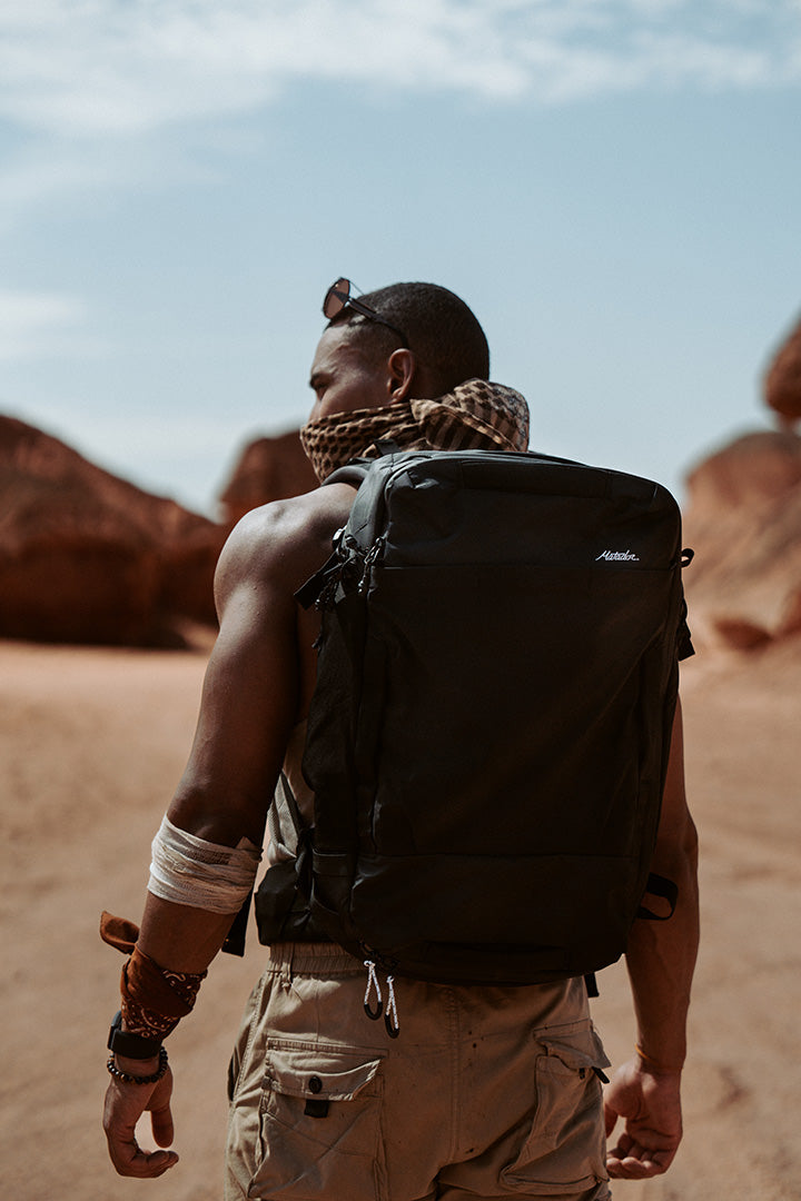 man wearing a backpack and buff in the desert