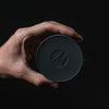 Hand holding canister lid on black background
