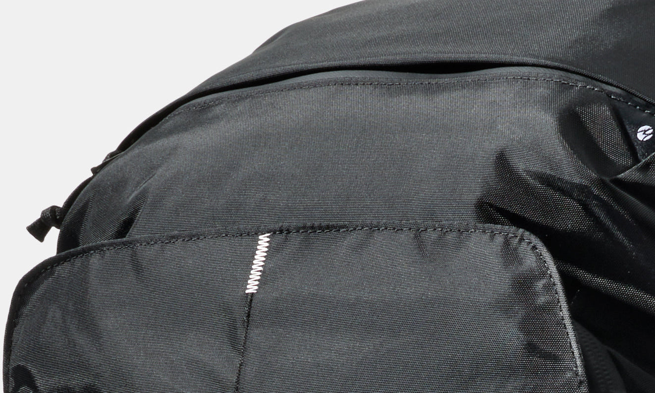 White Switchback Stitch™ on a black backpack with a light grey background