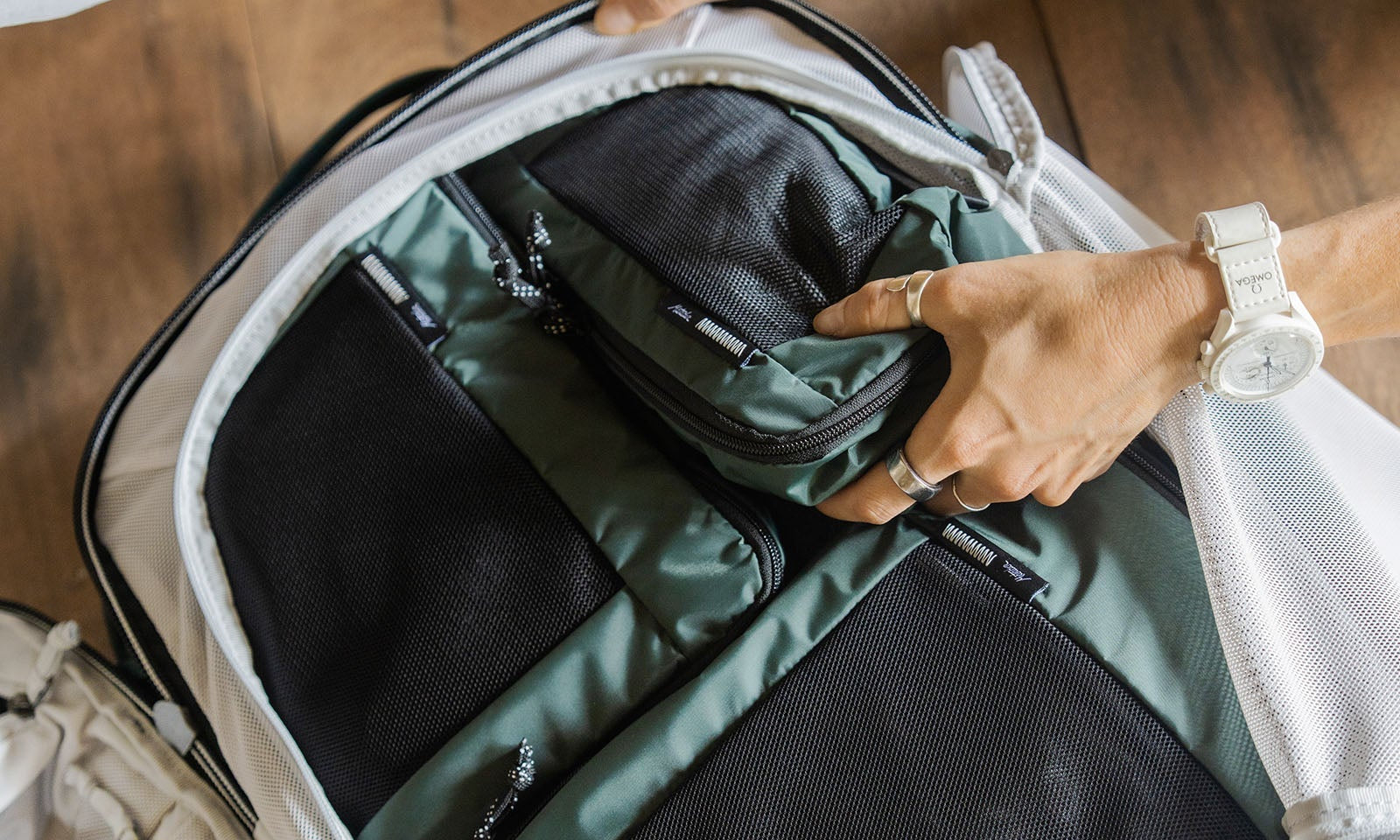 person's handed organizing an open green backpack, showing how to use packing cubes