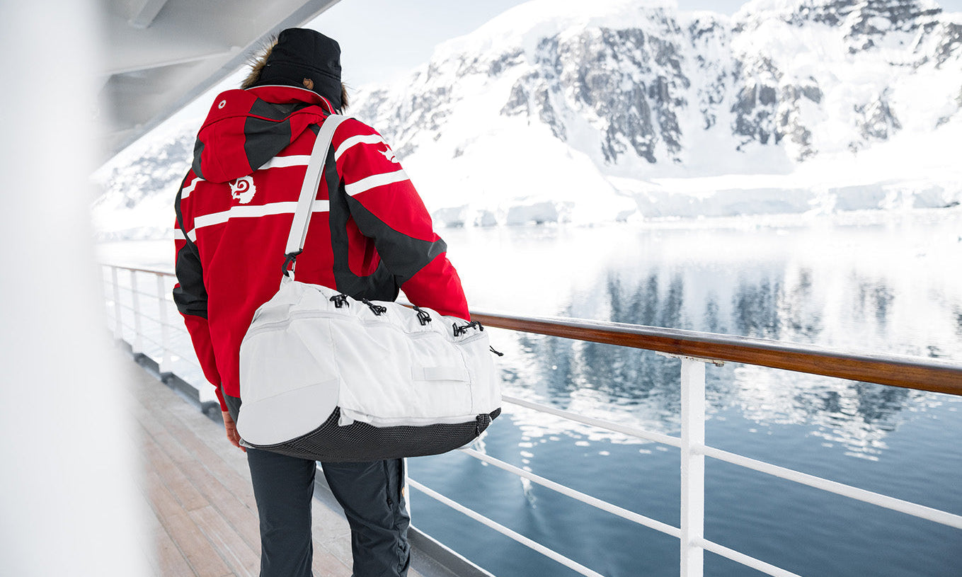 man wearing a white duffel bag while on an arctic cruise in Antarctica