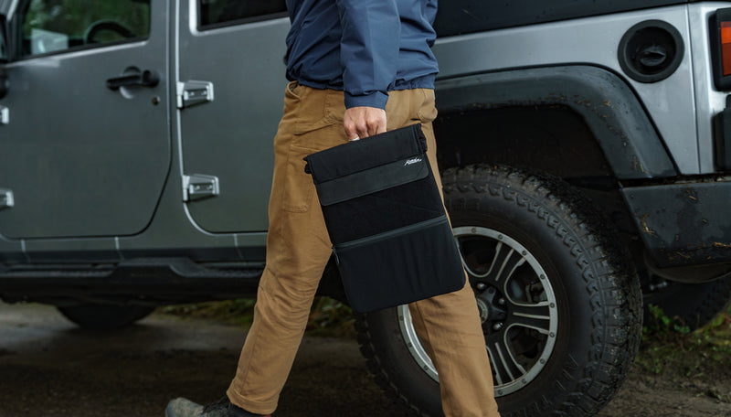 Man walking by Jeep, carrying a Laptop Base Layer
