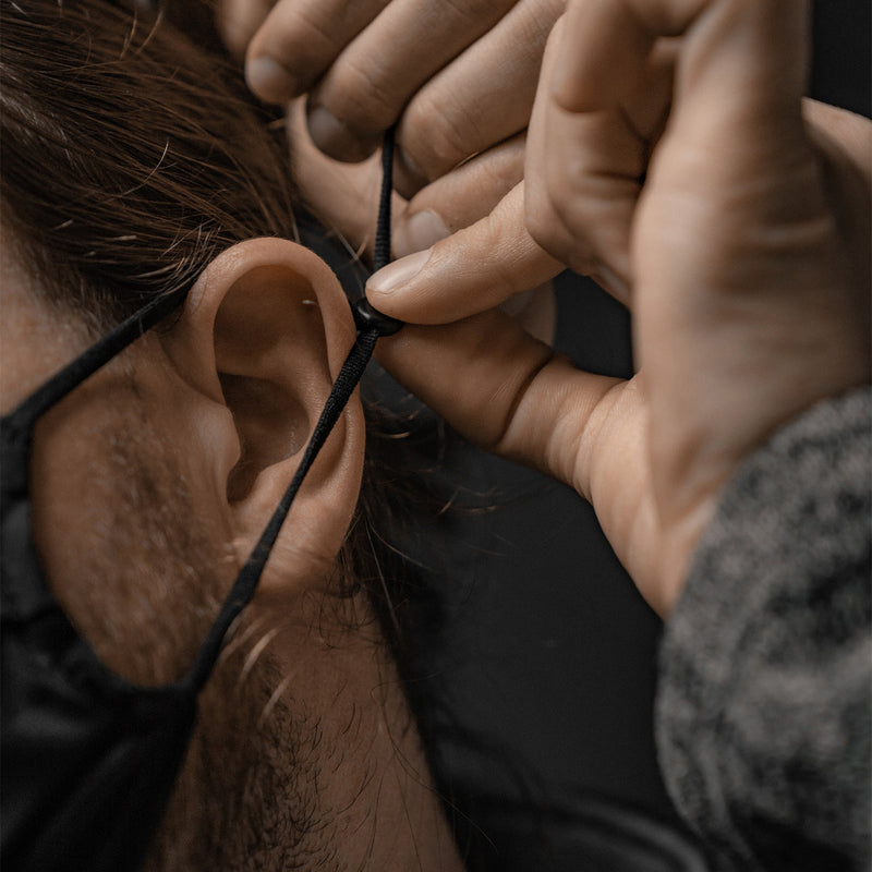 Man adjusting mask ear loop tightness