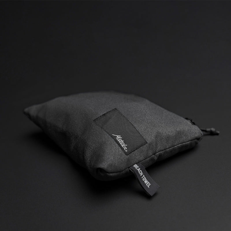 packed up charcoal beach towel shot on dark gray background