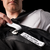 Man displaying contact information on gear tag attached to black backpack