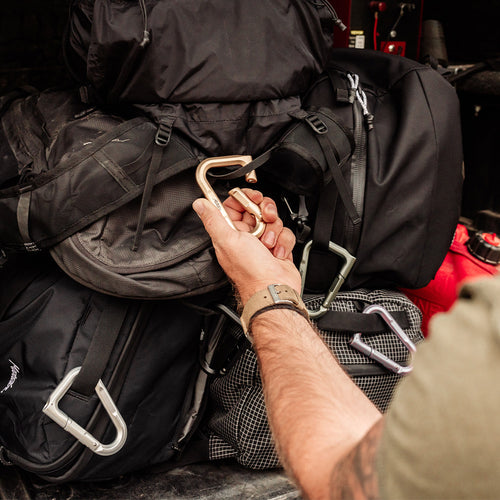 hands unclipping a gold betalock from a pile of bags covered in betalocks