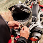 man clipping gold carabiner to motorcycle and helmet