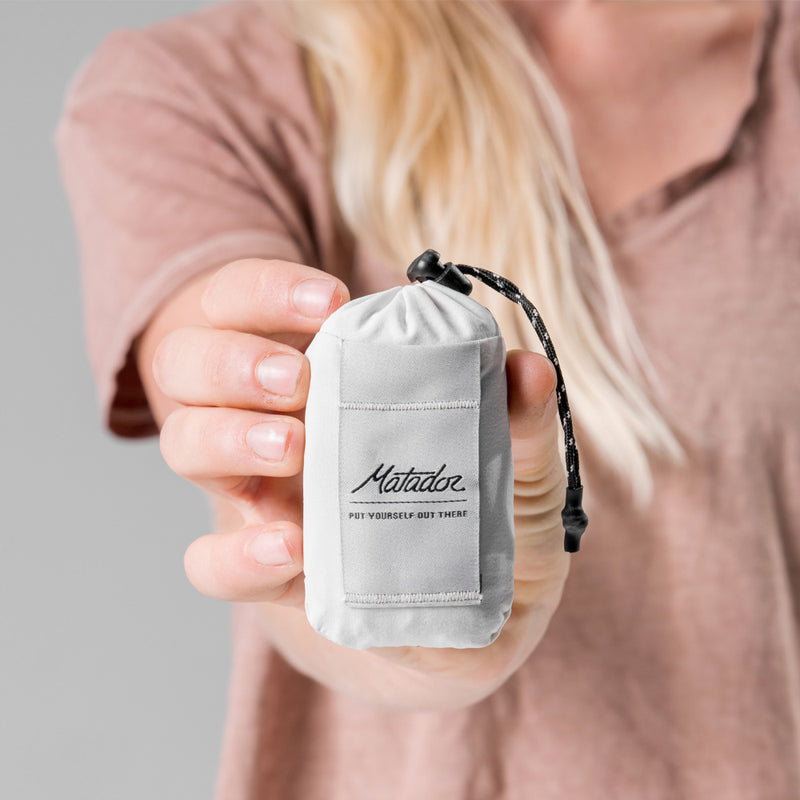 woman holding arctic white Pocket Blanket Mini to camera