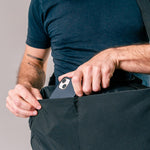 close up view of man pulling cell phone out of exterior black duffle pocket