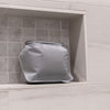 White toiletry case sitting in shower nook