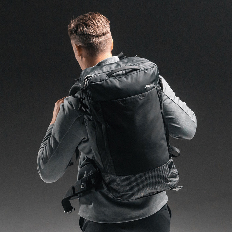 man on dark gray background wearing GlobeRider45 travel pack on his back