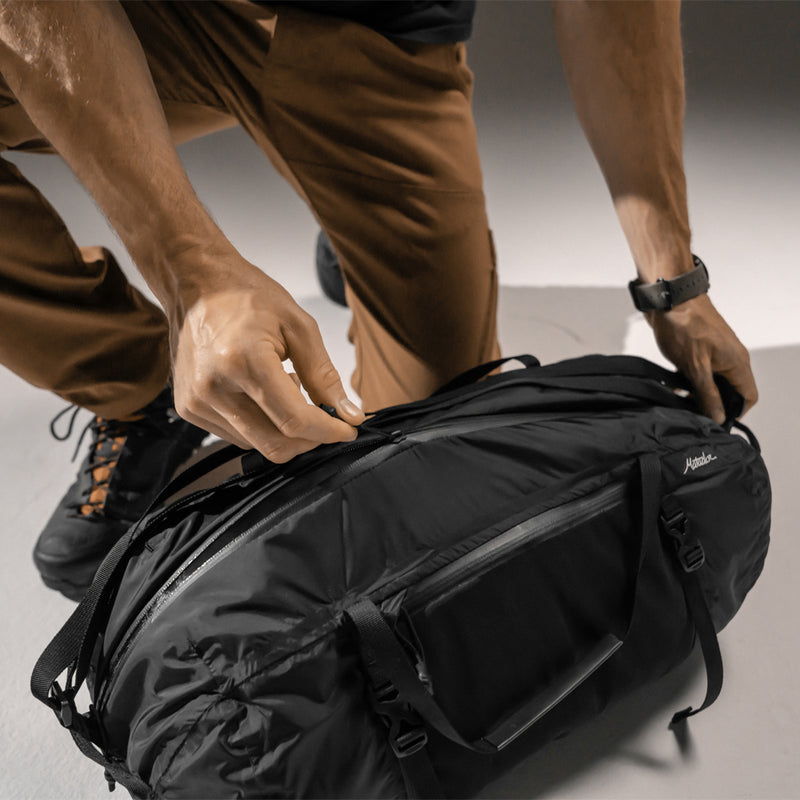 Man unzipping Freefly Duffle sitting on ground