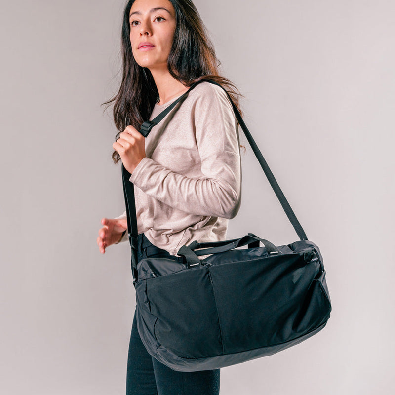 woman carrying black duffle by its shoulder strap