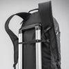 Black backpack sternum strap being used as a luggage handle passthrough