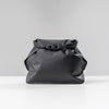 back view of black toiletry case on light gray background