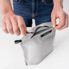 hands zipping white toiletry case open