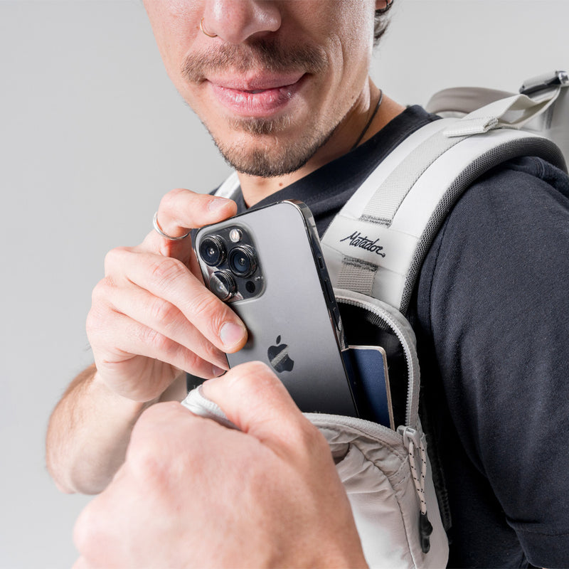 man wearing white speed stash, placing phone in the main pocket