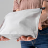 close up view of hands holding white zipper toiletry case