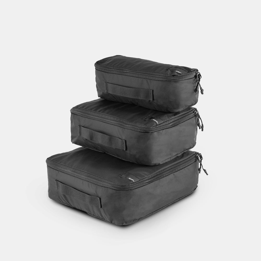 Black small, medium and large packing cubes stacked on a light gray background