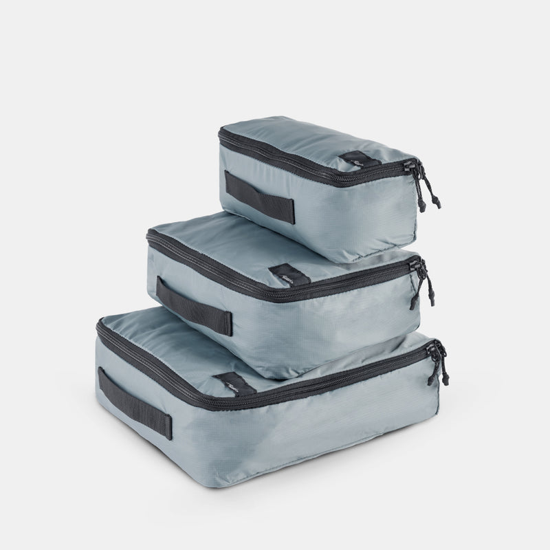 Slate small, medium and large packing cubes stacked on a light gray background
