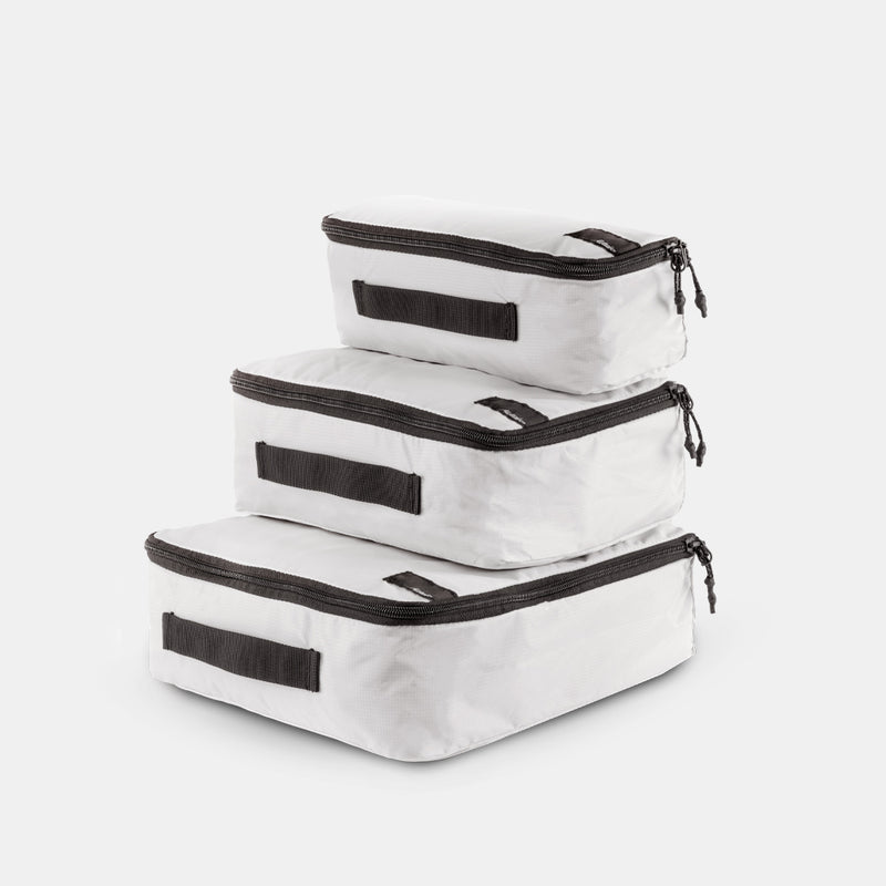 white small, medium and large packing cubes stacked on a light gray background