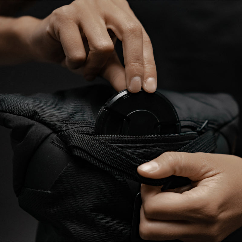 Hands placing lens cap into Camera Base Layer pocket