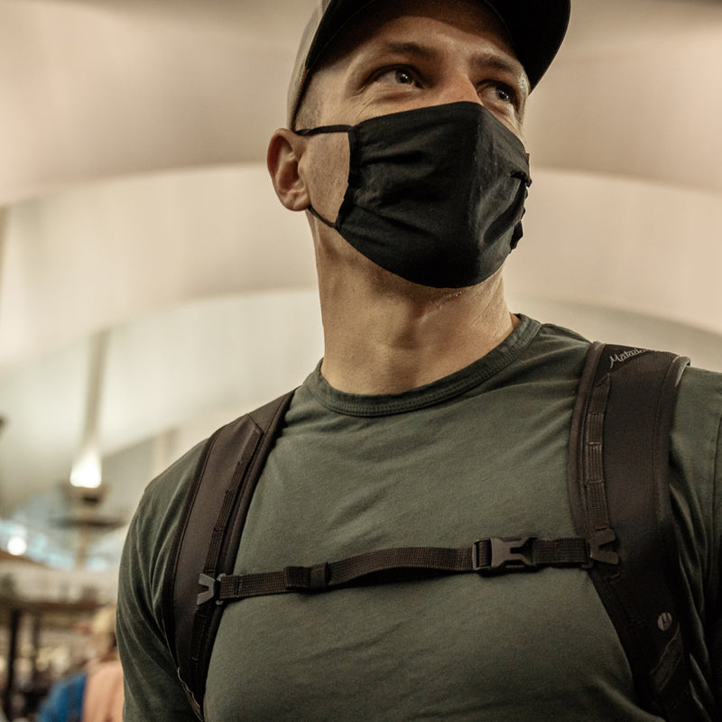 Man in train station, wearing black mask