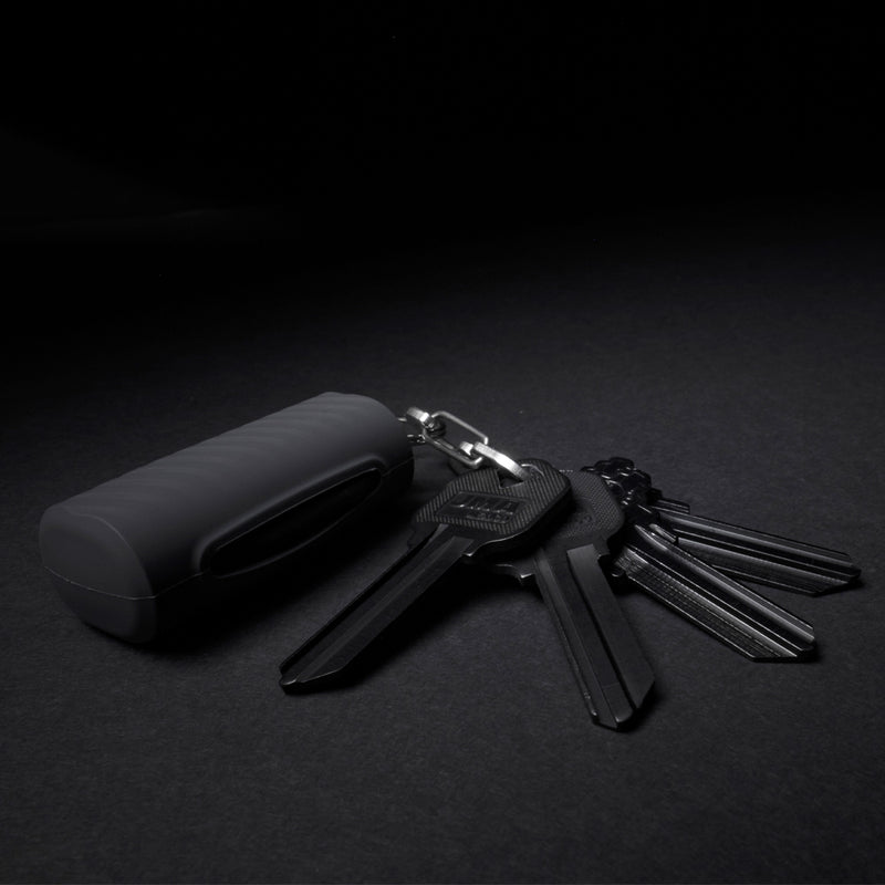 Keychain Mask case attached to set of black keys on black background