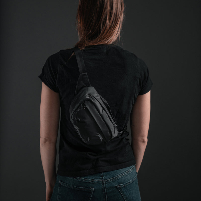 Woman on black background, wearing On-Grid Hip Pack across her back