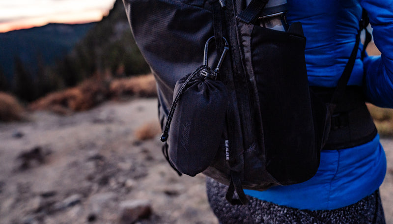 Packed up Ultralight towel clipped to the outside of a hiker's black backpack