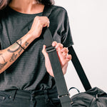woman adjusting shoulder strap of black duffle