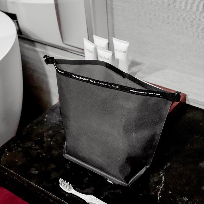 open charcoal toiletry case sitting on black marble counter top