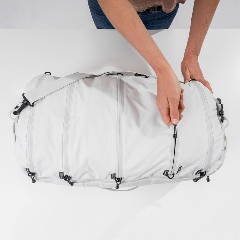 Woman with White SEG45 on white table, unzipping one of the segmented compartments