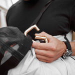 close up view of gold carabiner being clipped to bag with hat