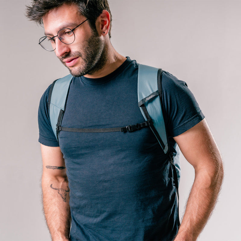 front view of man wearing slate blue backpack on light gray background