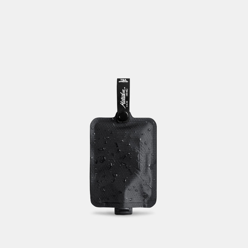 single charcoal toiletry bottle on light gray background