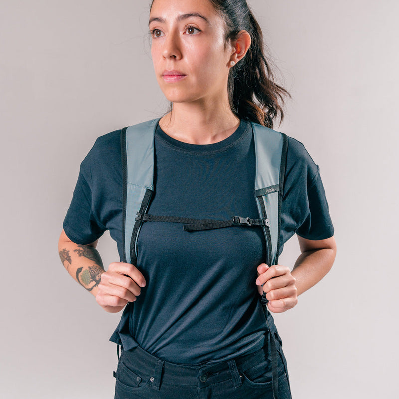 front view of woman wearing slate blue backpack on light gray background
