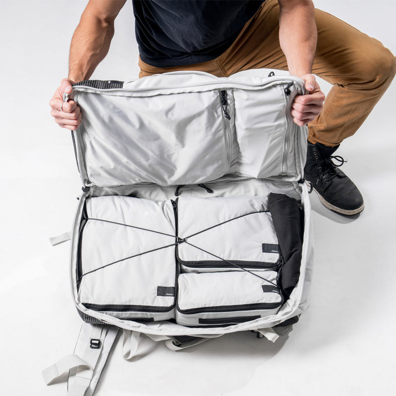 man showing the right clamshell pocket of the white Globerider45, full of white packing cubes