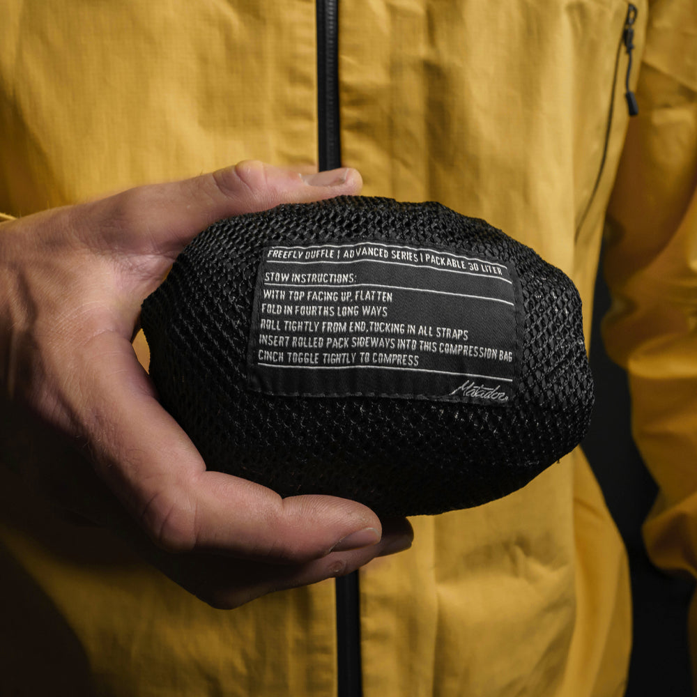 close up of man in yellow jacket holding a freefly duffle stuff sack