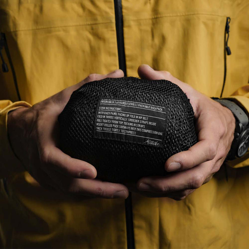 close up of man in yellow jacket holding a freerain28 stuff sack