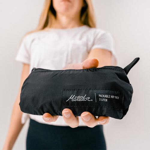 woman holding close up shot of packed down black sling bag