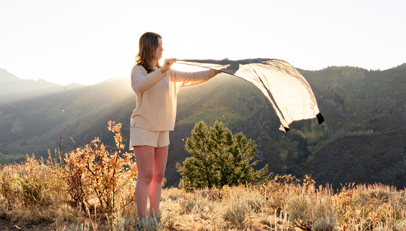 Woman laying down Pocket Blanket Mini in front of autumn mountain sunset